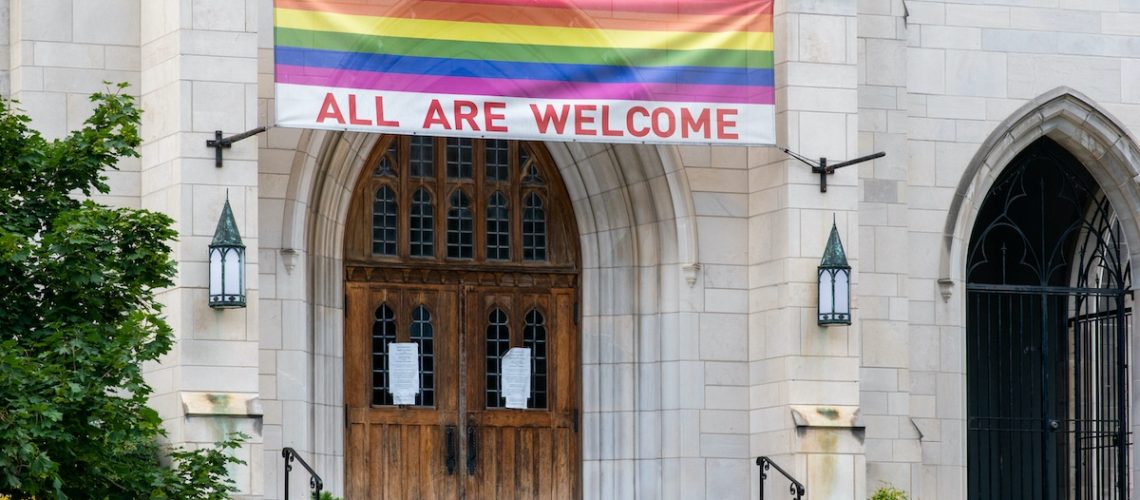 Washington, D.C. / USA - June 19 2020: Church in Washington is open to LGBT community with pride flag and "all are welcome" sign.